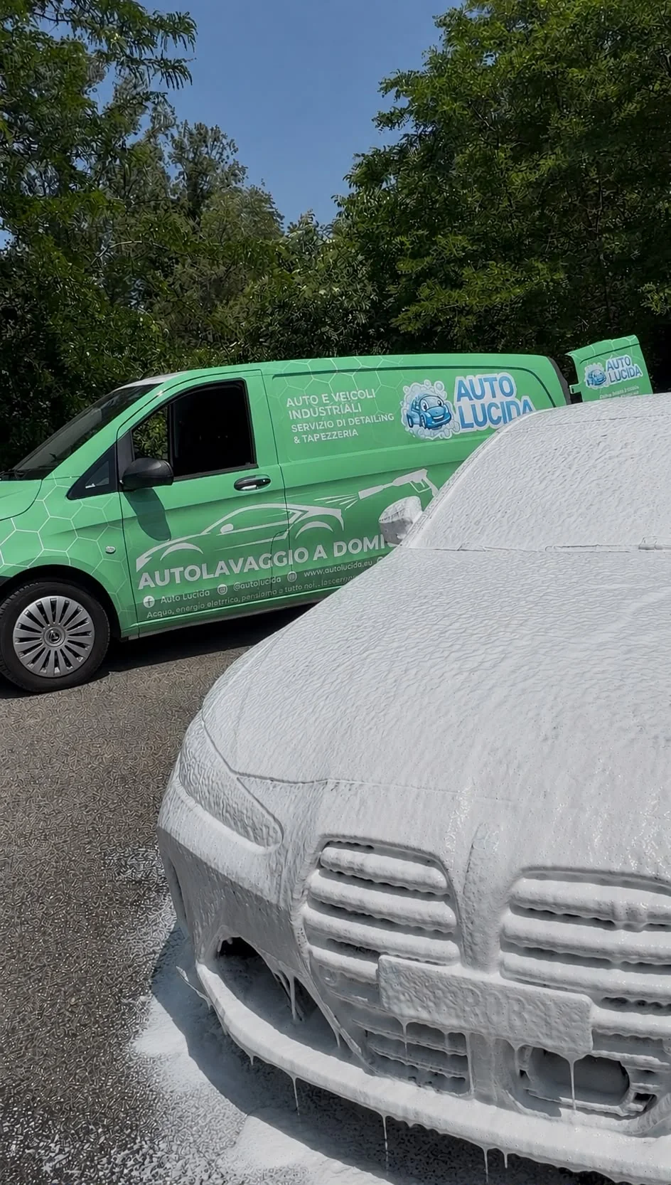 Auto ricoperta di schiuma durante il lavaggio accanto al furgone Auto Lucida